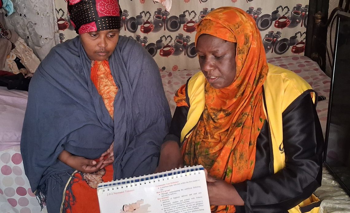 Abdulkadir Bajo with Aisha Hamisi in her house in the Eastleigh area, explaining the immunisation and nutrition calendar. Image Credit: Nigeria Health Watch