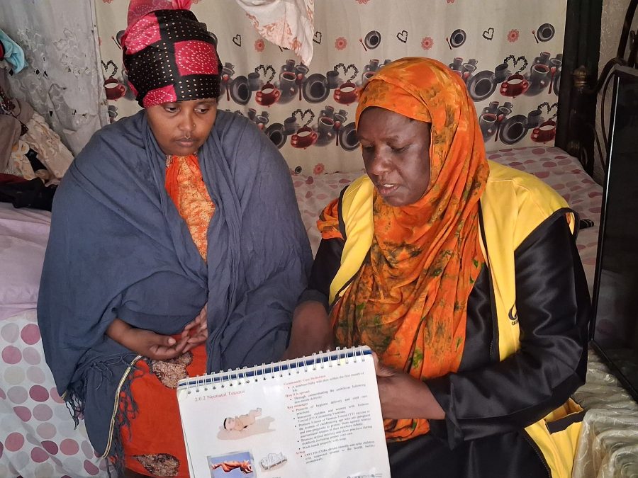 Abdulkadir Bajo with Aisha Hamisi in her house in the Eastleigh area, explaining the immunisation and nutrition calendar. Image Credit: Nigeria Health Watch